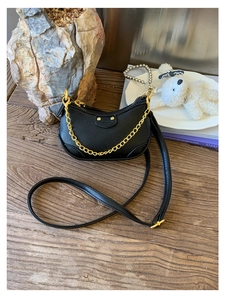 Détail du sac demi-lune en cuir noir avec chaîne dorée et accents de rivets