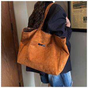 Grand sac cabas marron en daim avec doublure léopard montré sur l'épaule d'un mannequin