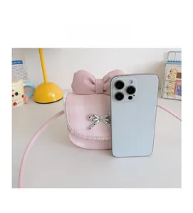 Size comparison of pink plaid crossbody bag with a smartphone and lace bow details