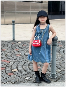 Detail of sweet blue denim dress with bow patterns and red polka dot mini chain bag