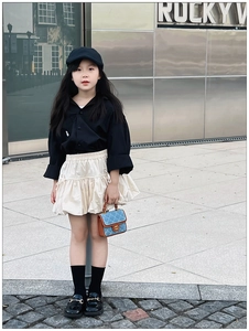 Girl in stylish quilted bag outfit posing against a modern metallic wall backdrop