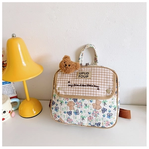 Detailed view of kids floral backpack featuring a cute brown plush bear charm detail