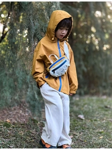 Close-up of kids waterproof crossbody bag styled with a yellow hooded windbreaker jacket