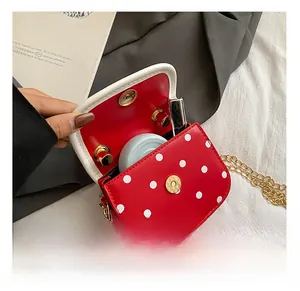 Interior detail of red polka dot mini bag showing capacity for cosmetics and gold chain