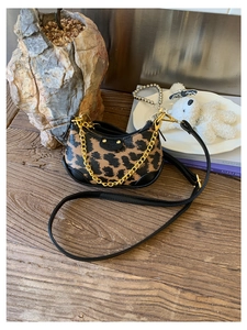 Gros plan du sac demi-lune léopard avec chaîne dorée et patch logo en cuir