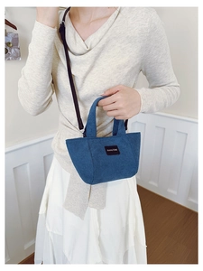 Sac seau en velours côtelé bleu avec bandoulière porté par un mannequin en tricot