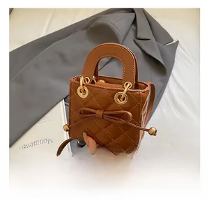 Close-up of brown quilted mini handbag with leather bow detail and metal ring handle