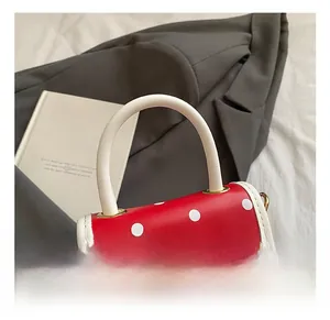 Detail of red polka dot mini bag featuring a golden bear logo and pearl-white handle