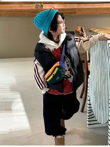 Close-up of kids casual crossbody bag paired with knit beanie and puffer vest outfit