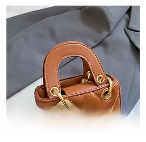 Detail of brown quilted mini handbag featuring a leather bow and golden metal hardware