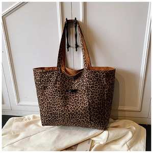 Détail du sac cabas en toile à imprimé léopard avec poche frontale sur porte en bois