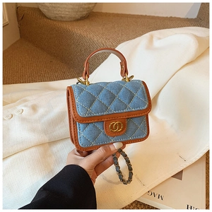 Detail of blue denim quilted mini bag with brown leather trim and golden ring hardware