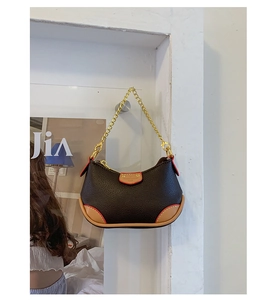 Detail of color-block leather dumpling bag with gold chain strap and red edge finish