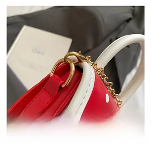 Detail of the high-quality gold metal hook and white handle on a red polka dot mini bag