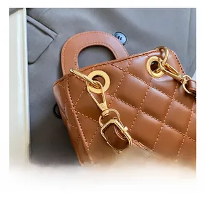 Detail of high-quality golden metal hooks on brown quilted mini handbag with PU leather