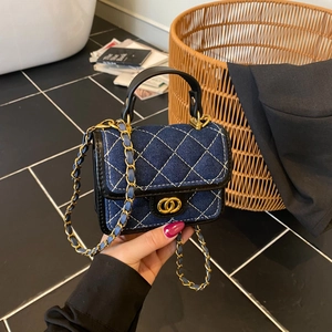 Close-up of denim quilted texture with gold hardware and chain strap on mini crossbody bag