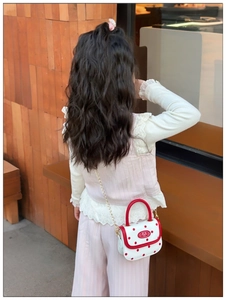Detail of red polka dot mini girl crossbody bag with gold chain and handle