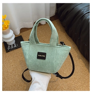Détail du sac seau en velours côtelé vert clair avec doubles anses et étiquette en cuir