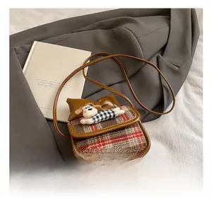 Detail of kids crossbody bag featuring 3D cartoon puppy, plaid bow, and brown leather texture
