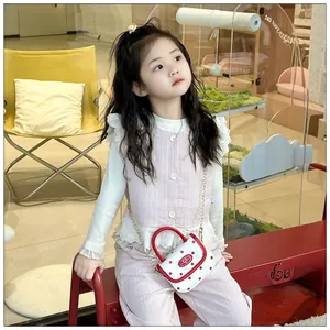 Detail of mini white leather bag with red polka dots and gold chain strap for girls
