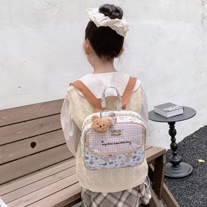 Floral canvas backpack for kids featuring a cute plush bear charm and plaid front pocket