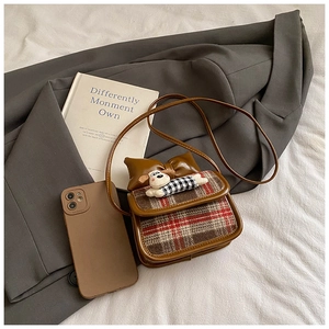 Detail of a brown plaid mini bag with cartoon dog and leather bow on a grey blazer