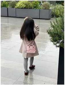 Pink quilted toddler handbag with bow detail worn by a child in an outdoor setting