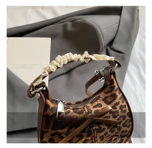 Dettaglio borsa leopardata per bambini con manici in pizzo e decorazione a fiocco