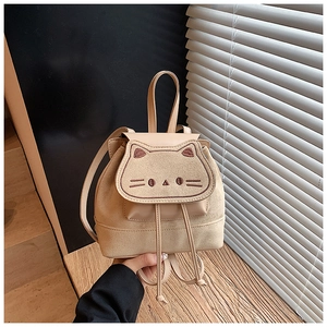 Detail of beige cartoon cat backpack featuring embroidered eyes and matte faux leather