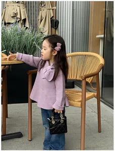 Close-up of child's purple knit sweater featuring a large decorative bow and soft texture