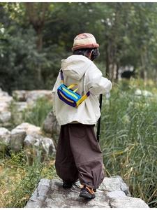Outdoor detail of a colorful tricolor crossbody chest bag for kids with yellow handle
