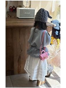 Detail of pink quilted mini crossbody bag styled with a girls autumn knit outfit