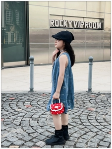 Close-up of red polka dot mini bag for girls paired with denim dress and beret