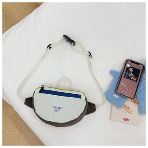 Close-up of a kids' color-block chest bag with adjustable strap and buckle on a white bed