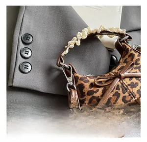 Dettaglio della borsa leopardata con finiture in pelle, fiocco e manico in pizzo