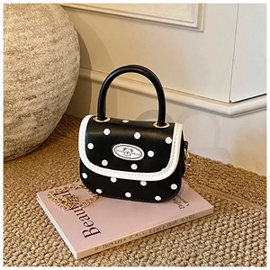 Detail of polka dot mini bag with bear emblem and golden metal chain strap