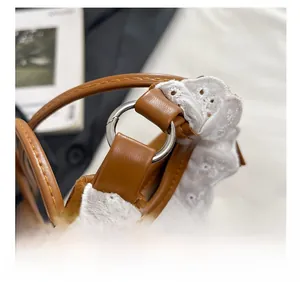 Détail du sac en cuir marron avec bordure en dentelle blanche et anneaux en métal
