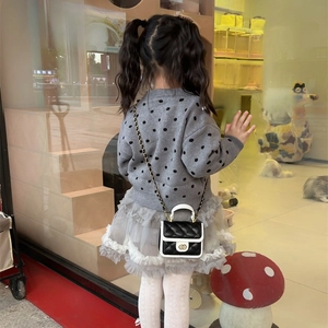 Girl wearing black quilted chain bag with white trim and gold handle in elegant style