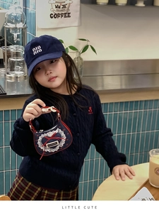 Detailansicht der Mini-Denim-Mädchentasche mit Spitze, roter Schleife und Metalletikett