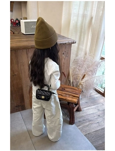 Mini black quilted shoulder bag for girls with gold hardware shown on child model