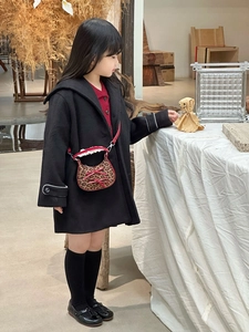 Dettaglio borsa leopardata per bambini con fiocco rosso e cappotto di lana nero elegante