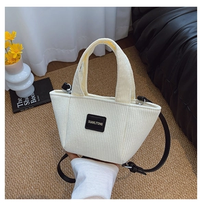 Détail du sac seau en velours côtelé crème avec logo noir et bandoulière amovible