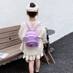 Mädchen mit lila Paillettenflügel-Rucksack und niedlichem Meerjungfrauen-Motiv im Freien