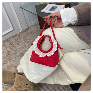 Détail du mini sac à main rouge en daim avec dentelle blanche et fines anses en cuir