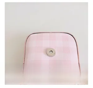 Detail view of pink plaid bag showing silver magnetic closure and fine stitching