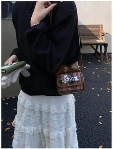 Close-up of kids plaid crossbody bag with puppy plush and bow detail in outdoor setting