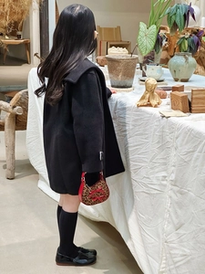 Dettaglio bambina con cappotto nero e borsa leopardata rossa con fiocco elegante