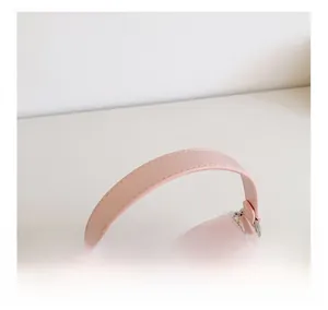 Detailed shot of pink leather handle with silver bow buckle and delicate lace trim