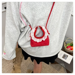 Détail du mini sac rouge en daim avec décoration en dentelle blanche sur la poignée
