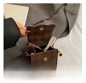 Détail de la pochette à carreaux marron montrant l'espace intérieur et le fermoir magnétique